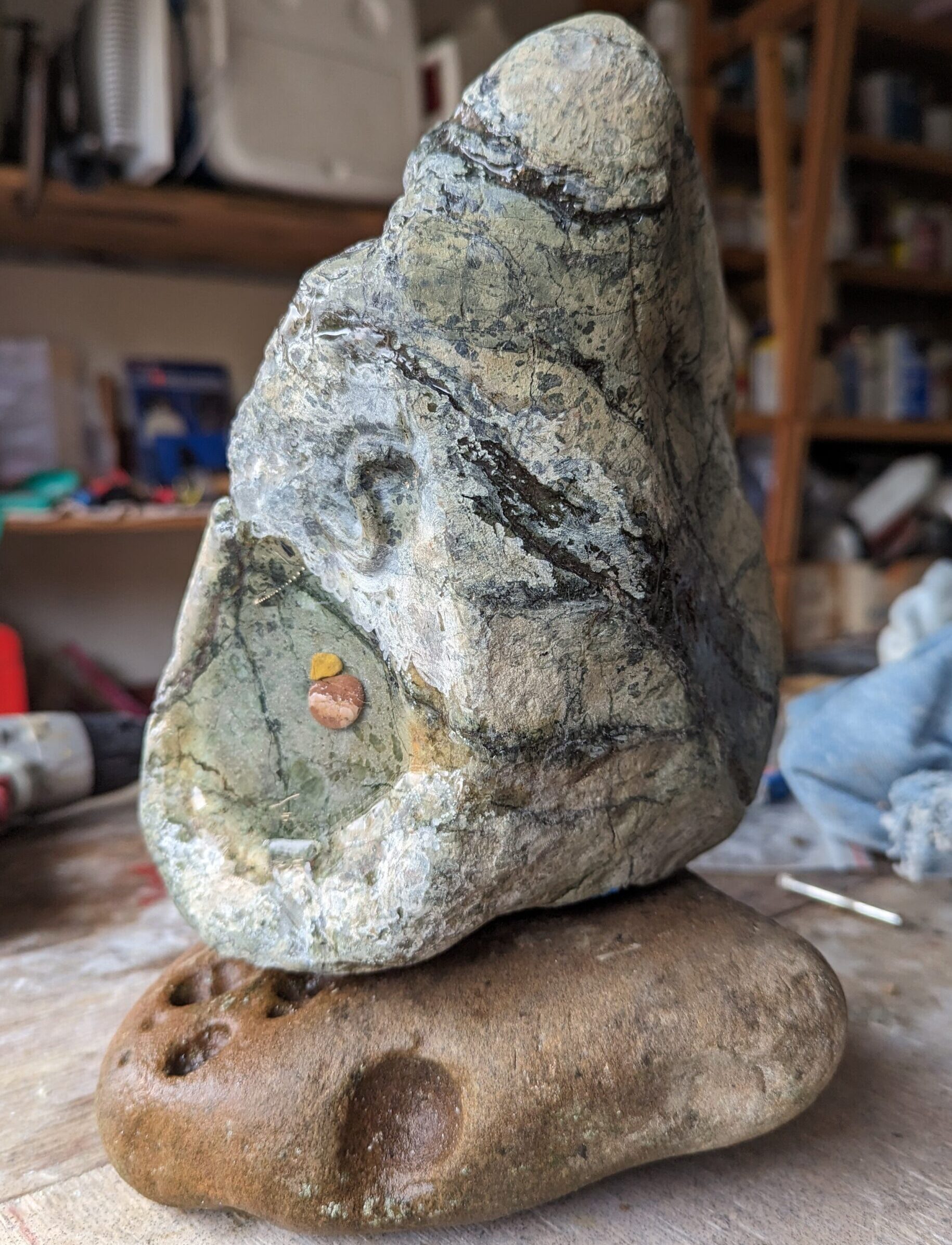 Photo of an altered green rock mounted to a worn sandstone rock